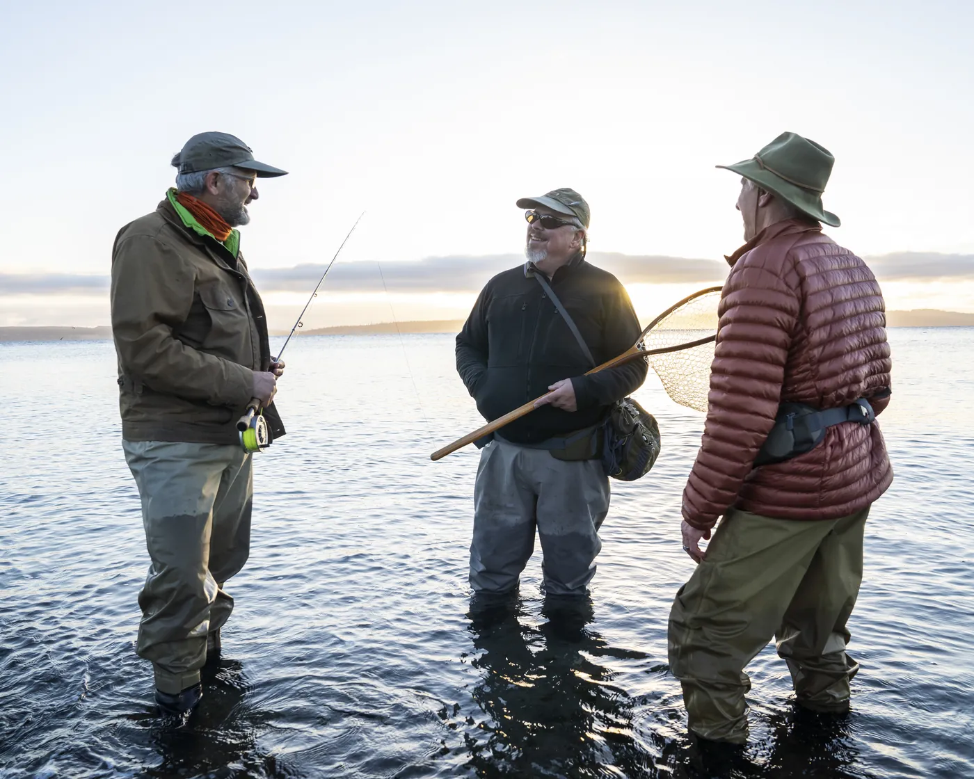 Three anglers in waders talking in the water on a fishing trip