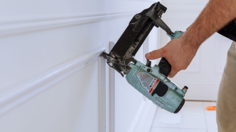 Carpenter using a brad nail gun to complete framing trim Air gun for nailing